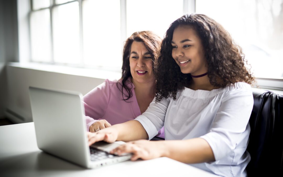 A Mother And Teenage Daughter Looking At Laptop Together